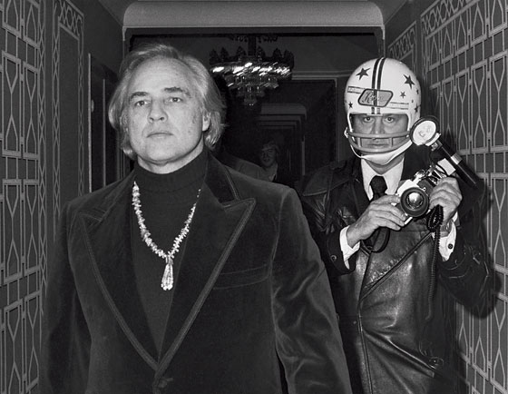 Marlon Brando seguito da Ron Galella protetto da un casco (1974)