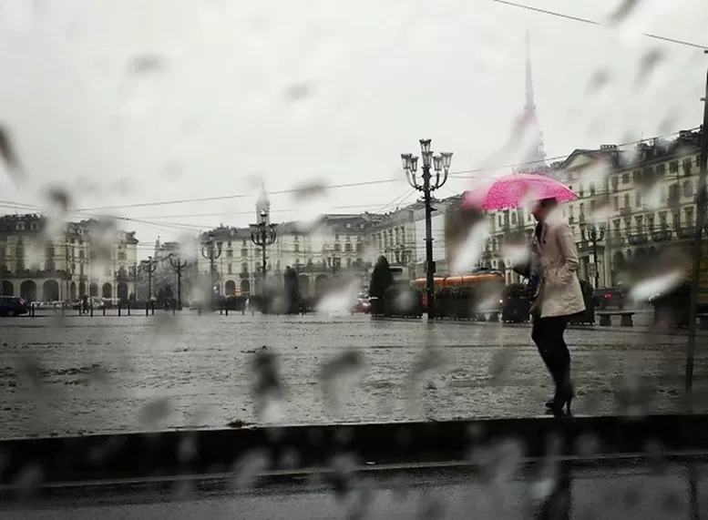 signora sotto la pioggia con ombrello rosa in piazza Vittorio con Mole Antonelliana sullo sfondo