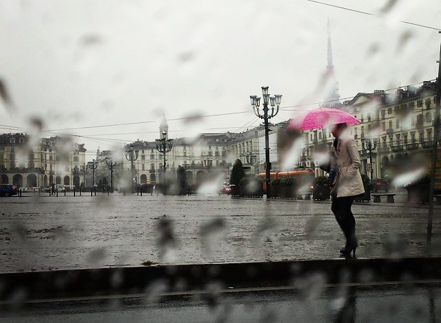 donna con ombrello rosa sotto la pioggia di piazza Vittorio a Torino