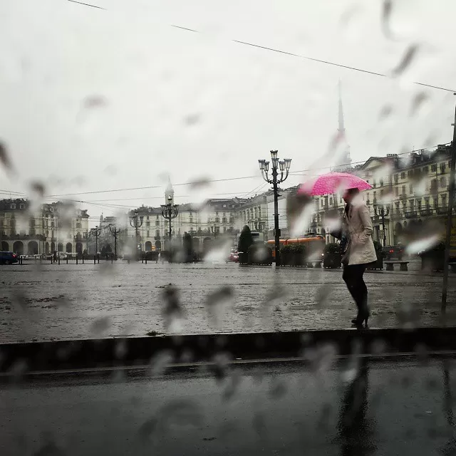 donna con ombrello rosa sotto la pioggia di piazza Vittorio a Torino