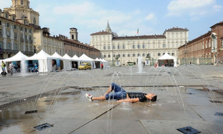 Ragazzo sdraiato sotto la fontana di piazza Castello a Torino un caldo giorno d'estate