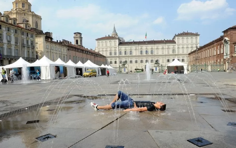 Ragazzo sdraiato sotto la fontana di piazza Castello a Torino un caldo giorno d'estate