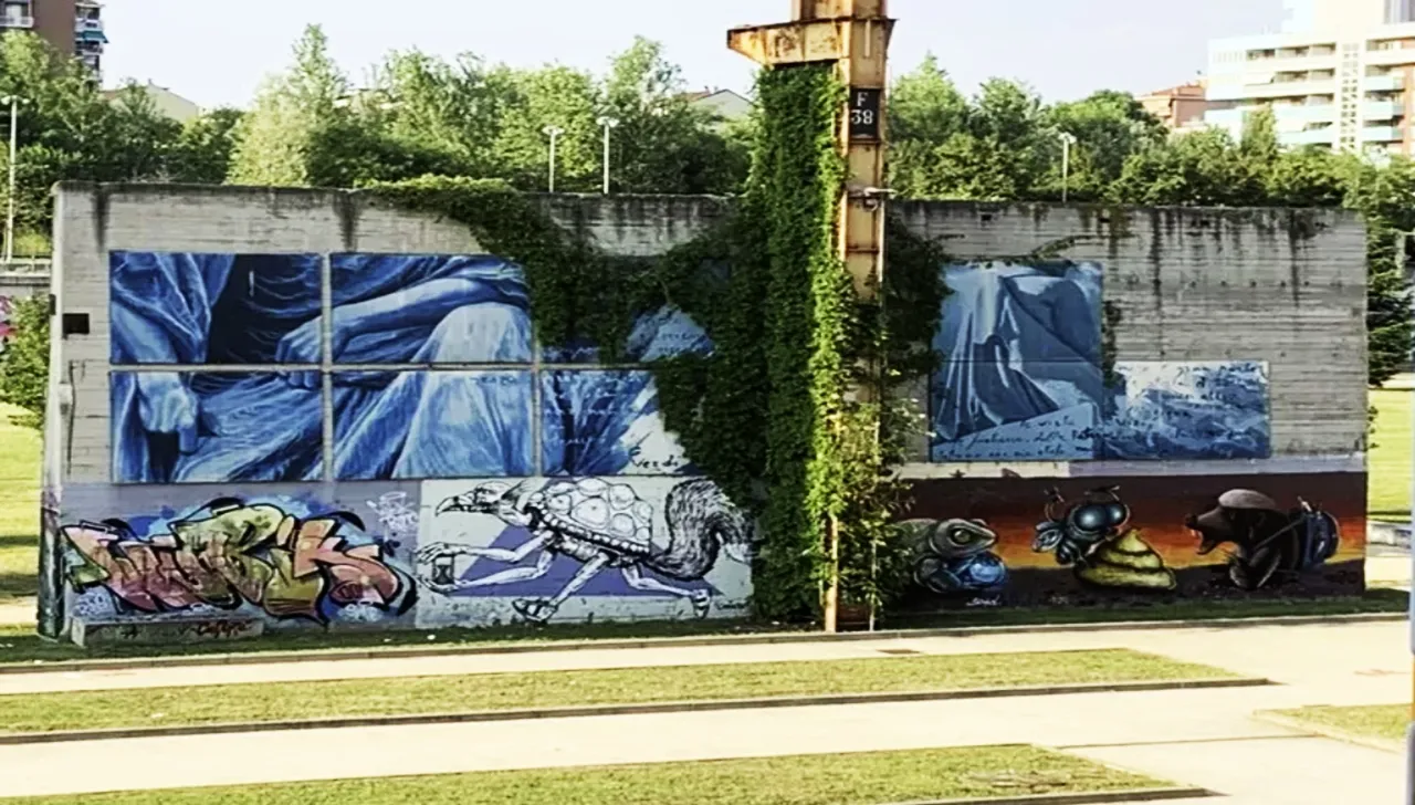 Murale anti-smog nel quartiere Aurora a Torino, realizzato con vernici fotocatalitiche per assorbire l'inquinamento. L'opera di street art, situata tra Via Gené e Corso Regio Parco, raffigura figure umane in blu e creature fantastiche, contribuendo alla riqualificazione urbana e alla sostenibilità ambientale