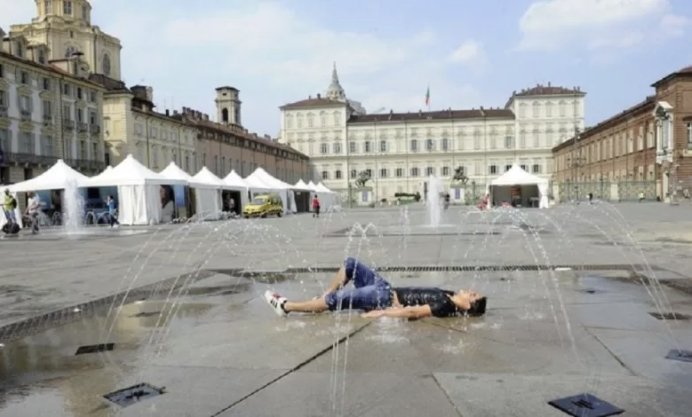 Ragazzo sdraiato sotto la fontana di piazza Castello d'estate