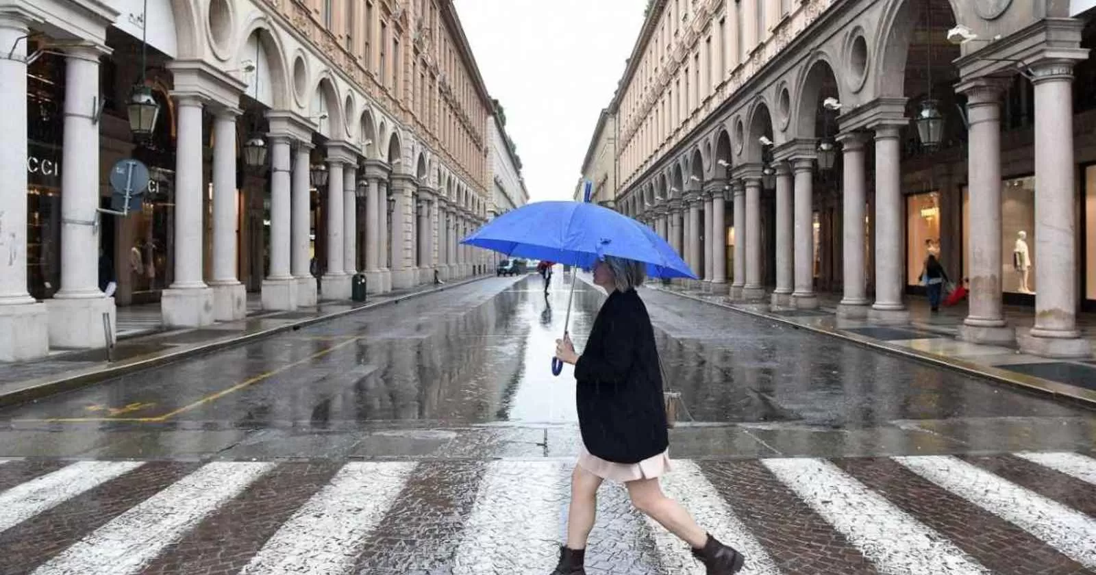 ragazza sotto la pioggia con ombrello blu