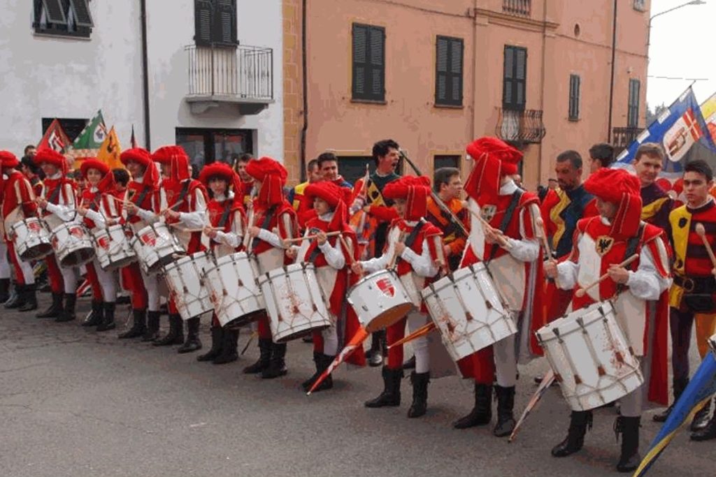 ragazzi con vestiti medievali rossi suonano tamburello