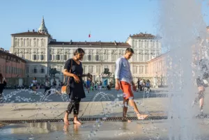 ragazzi scalzi camminano nella fontana di piazza Castello a Torino