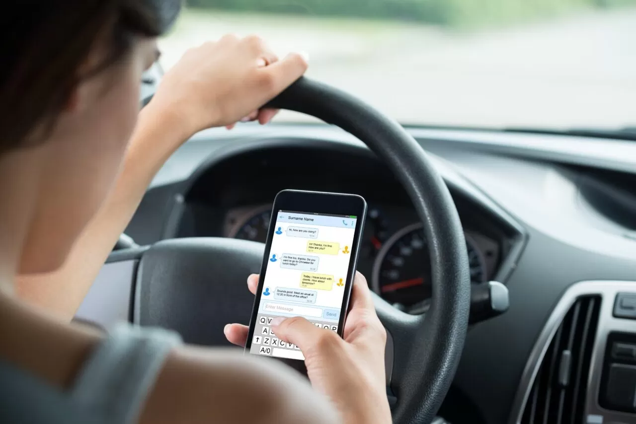 ragazza guarda il cellulare mentre guida