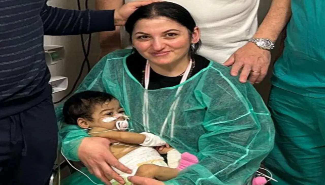 Mamma con neonata in braccio dopo operazione, camice verde della donna