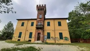 Facciata principale di Villa Govean ad Alpignano, edificio storico con torre centrale in mattoni e pareti gialle, attualmente in fase di riqualificazione