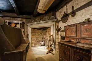 Cucina contadina storica del Seicento al Museo delle Langhe nel Castello di Grinzane Cavour, con camino in pietra, mobili rustici e utensili tradizionali