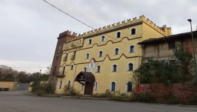 Facciata principale del Castello Bramafame di Torino, edificio giallo con merlature neomedievali e torre in mattoni nella zona delle Basse di Stura, attualmente in stato di abbandono.