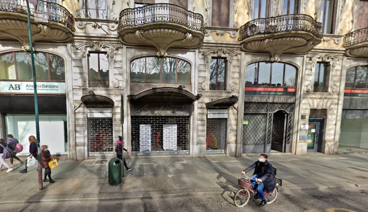 Facciata in stile liberty di Palazzo Priotti a Torino, con balconi decorati e ingresso chiuso dell’ex cinema Ambrosio su corso Vittorio Emanuele II, vista da strada con passanti e ciclista in primo piano