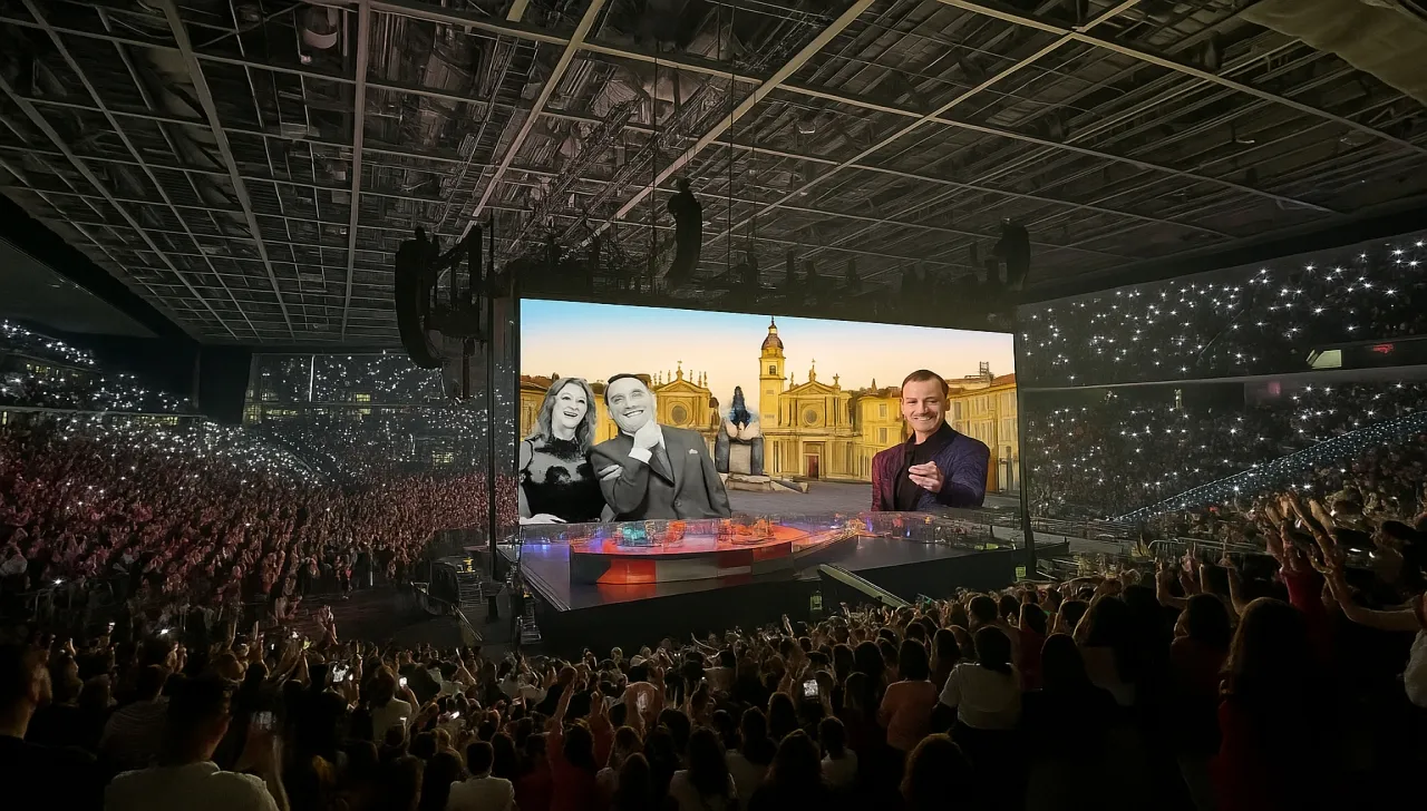 pubblico all'Inalpi Arena assiste a un concerto con al centro una band musicale e sopra uno schermo che mostra piazza San Carlo a Torino