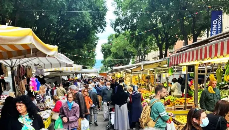 Mercato rionale di Santa Rita a Torino in corso Sebastopoli, con banchi di frutta e verdura affollati di clienti e ambulanti