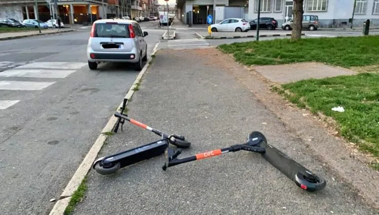 Due monopattini elettrici abbandonati a terra su un marciapiede a Torino