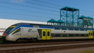treno sfreccia sui binari davanti all'entrata del centro commerciale Le Gru a Grugliasco (Torino)