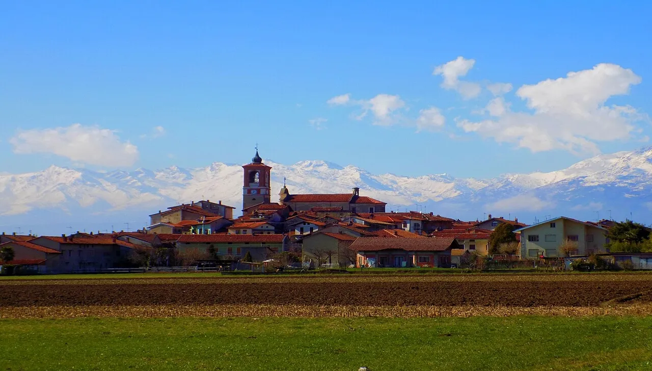 Borgo di Palazzo Canavese visto da lontano, dietro un prato verde di giorno