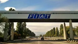 Ingresso dello stabilimento Fiat Rivalta di Torino con passerella pedonale sopraelevata e logo storico dell'azienda
