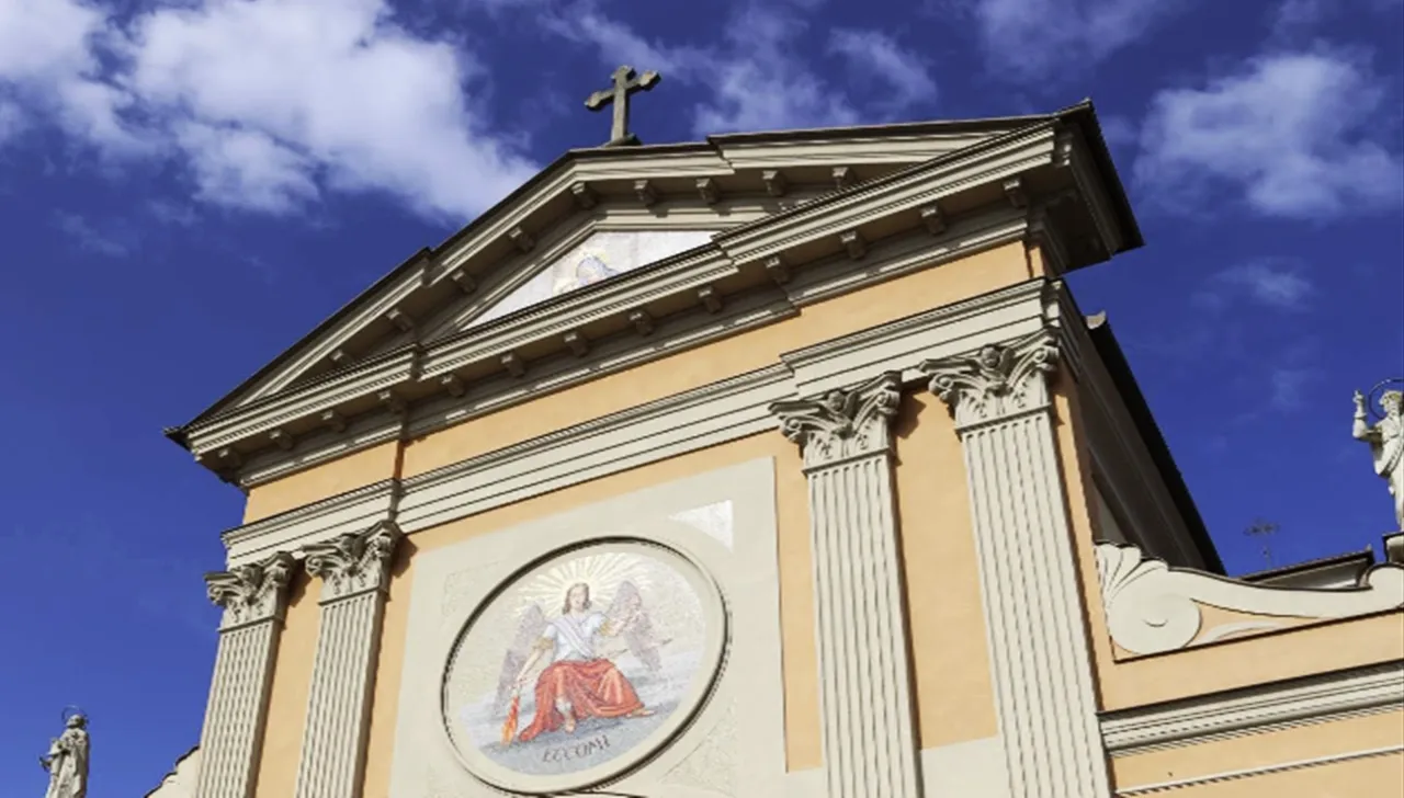 Facciata della Chiesa di San Michele Arcangelo a Rosta con colonne e mosaico centrale sotto un cielo terso