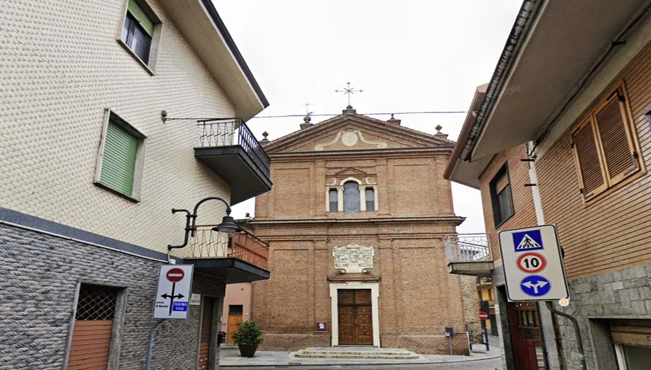 Facciata in mattoni della Chiesa del Santissimo Nome di Gesù a Pianezza vista da via XXV Aprile, incorniciata dalle case del centro storico